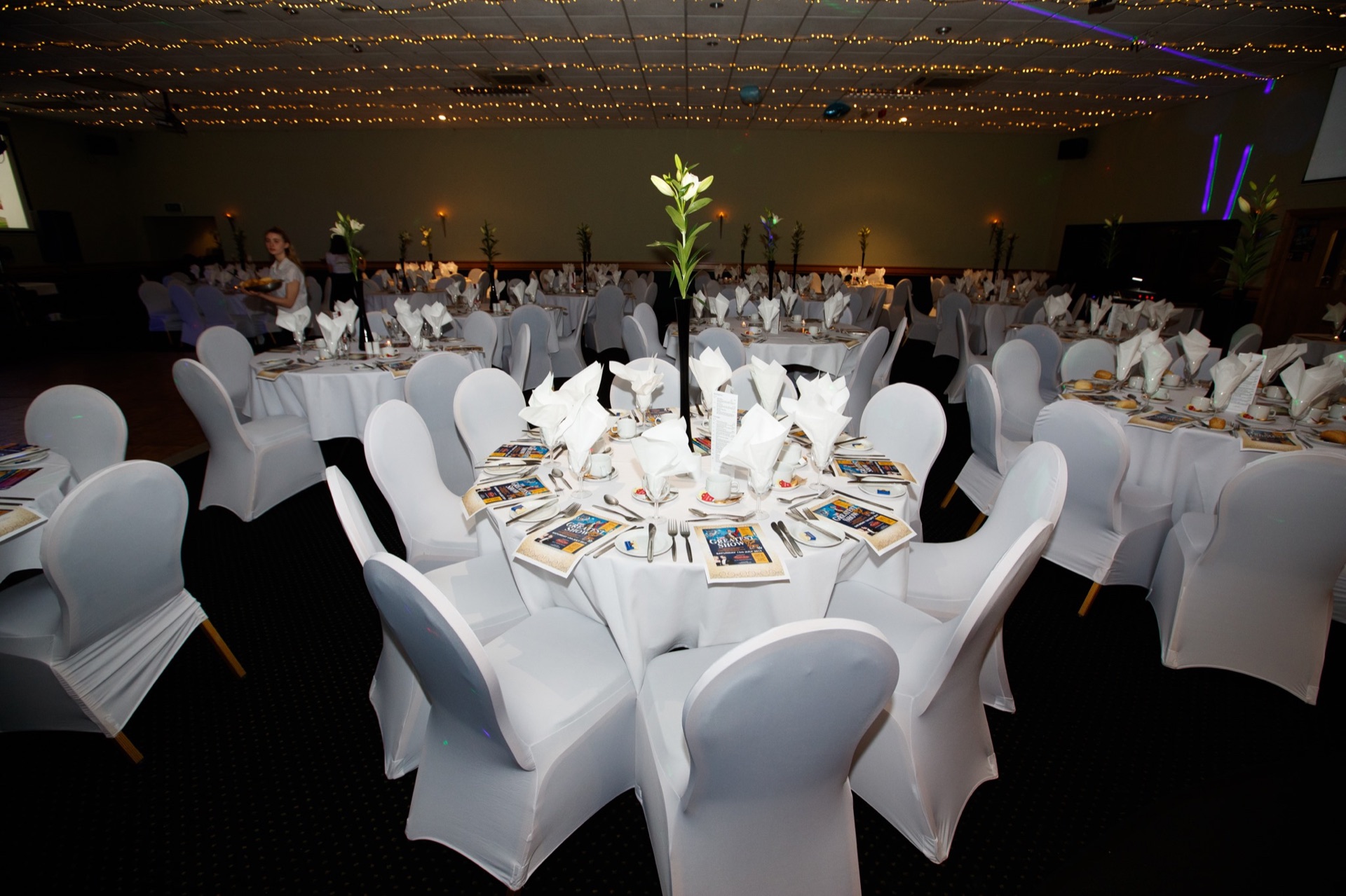 The Premier Suite set for a banquet with white chair covers and a fairy-light ceiling canopy